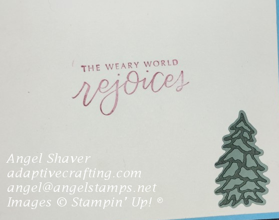 Card inside with evergreen tree die and sentiment "This weary world rejoices."