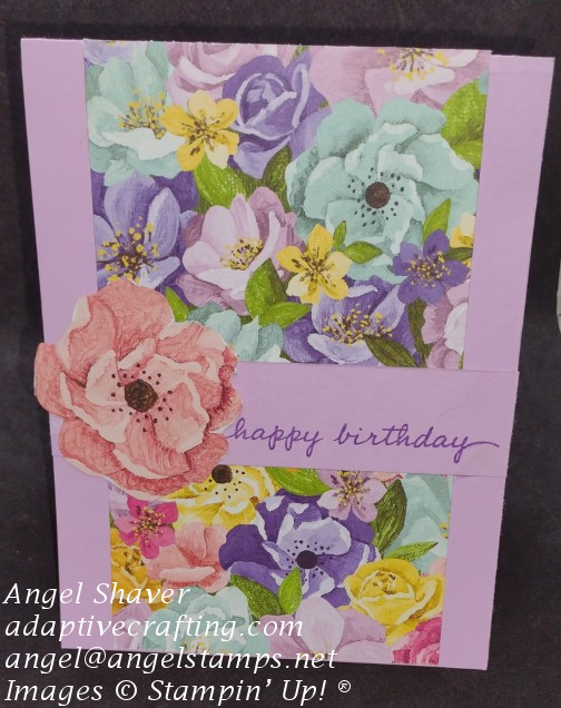Light purple birthday card made with vertical panel of patterned paper with lots of colored flowers and die cut pink flower on "happy birthday" sentiment strip.