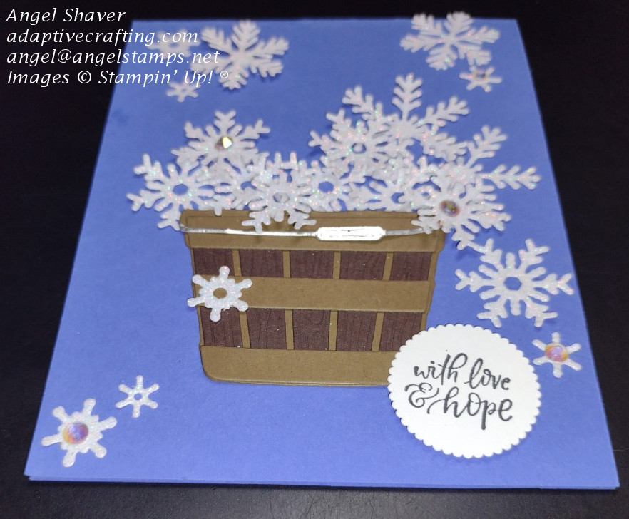 Blue card with die cut basket catching snowflakes falling from the top of the card.  Basket is filling up and spilling over.  Chrismas sentiment circle says "with love & hope"