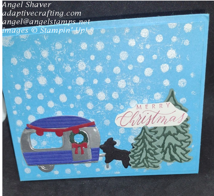 Turquoise Christmas card with heat embossed white dots representing snowfall on a camping scene with camper decorated for Christmas, puppy dog, and evergreen trees.  Sentiment says "Merry Christmas"