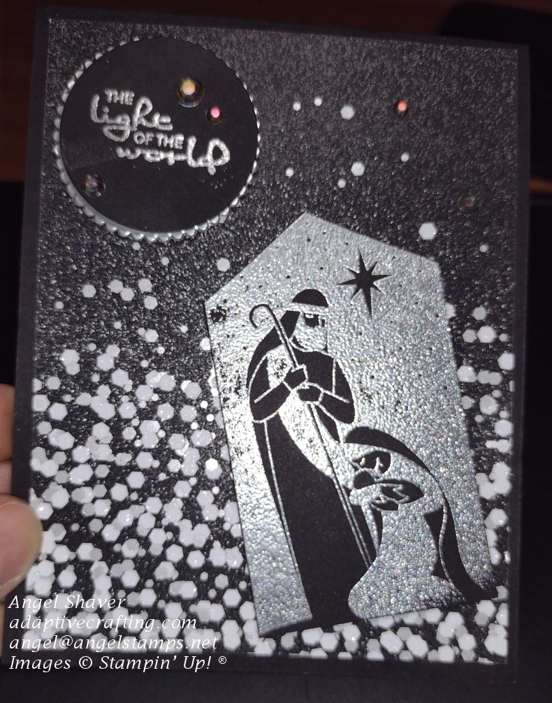 Black Christmas card with silver sparkles black paper and silver heat embossed holy family.  Sentiment says "The Light of the World."
