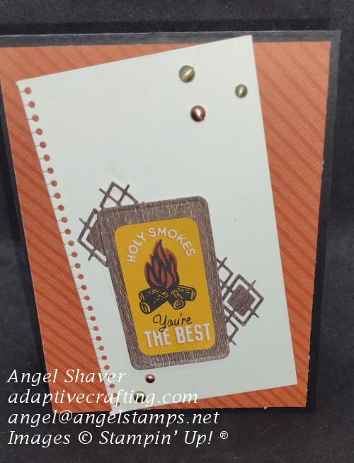 Black card with rust orange paper layer with diagonal stripes.  Then layer of white paper with spiral bound torn edge.  Finally, layers of wood grain paper dies topped with a wood grain rectangle frame with sentiment die that say, "Holy Smokes You're the Best" with campfire image.