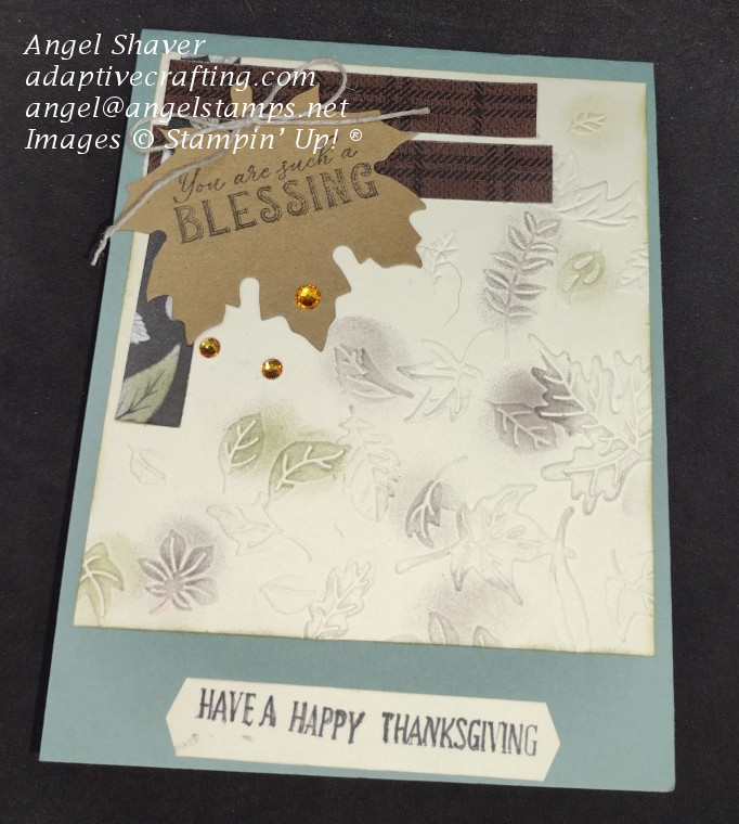 Green Thanksgiving card with embossed leaves and strips of patterned paper.  Brown and green are sponged onto some leaves.  Kraft leaf die is added to top of card with linen bow and sentiment "You are such a blessing" stamped on it.  "Have a happy Thanksgiving" sentiment at the bottom of the card front.