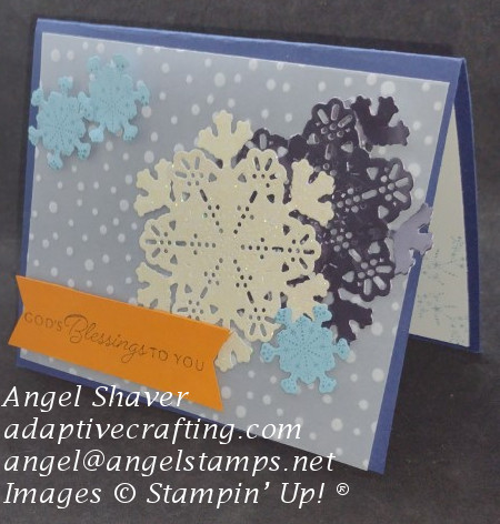 Navy Christmas card with vellum snowflake background.  Die cut snowflakes decorate front--large vanilla glimmer, large silver foil, small blue cardstock snowflakes.  Orange sentiment label reads, "God's blessings to you."