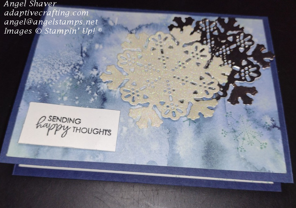 Navy winter birthday card with lots of stamped snowflakes on background paper that looks like a winter sky.  Two large snowflake die cuts added--one in vanilla glimmer and one in silver foil.  Sentiment label says "Sending happy thoughts."