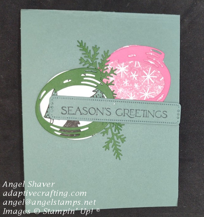 Green Christmas card featuring two circles of patterned paper: one pink with snowflakes/star bursts and the other with Christmas trees.  Die cut evergreen branches run between the circles.  Sentiment rectangle says "Seasons Greetings."
