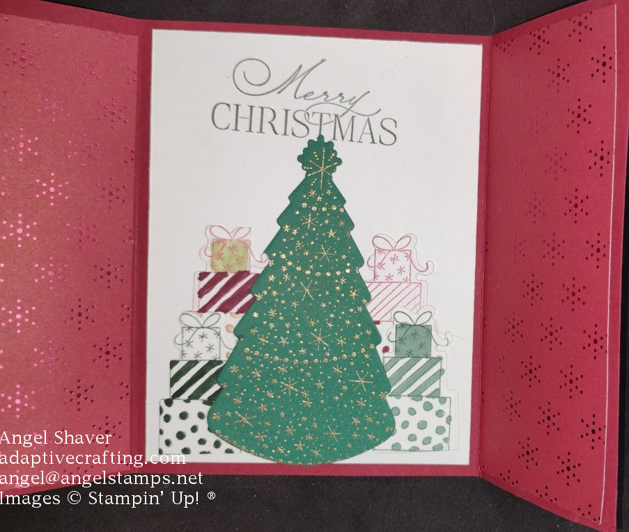 Inside of card with Chruistmas tree die heat embossed with gold ornaments.  Tree is surrounded by four piles of gifts.  Top of card says, "Merry Christmas."  The inside of both door panels are covered with red festive foil.