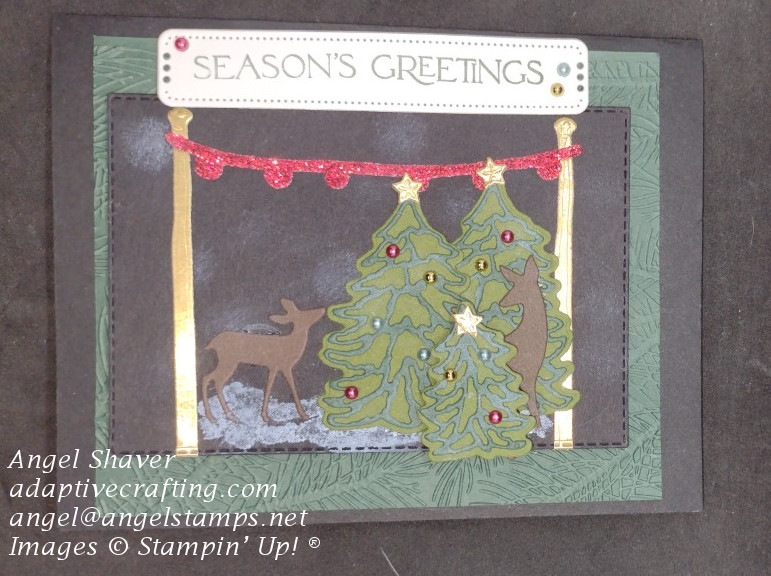 Black Christmas card with green card layer embossed with pine branches and black rectangle showcasing a snowy scene of deer among decorated Christmas trees .  Sentiment says, "Seasons Greetings."