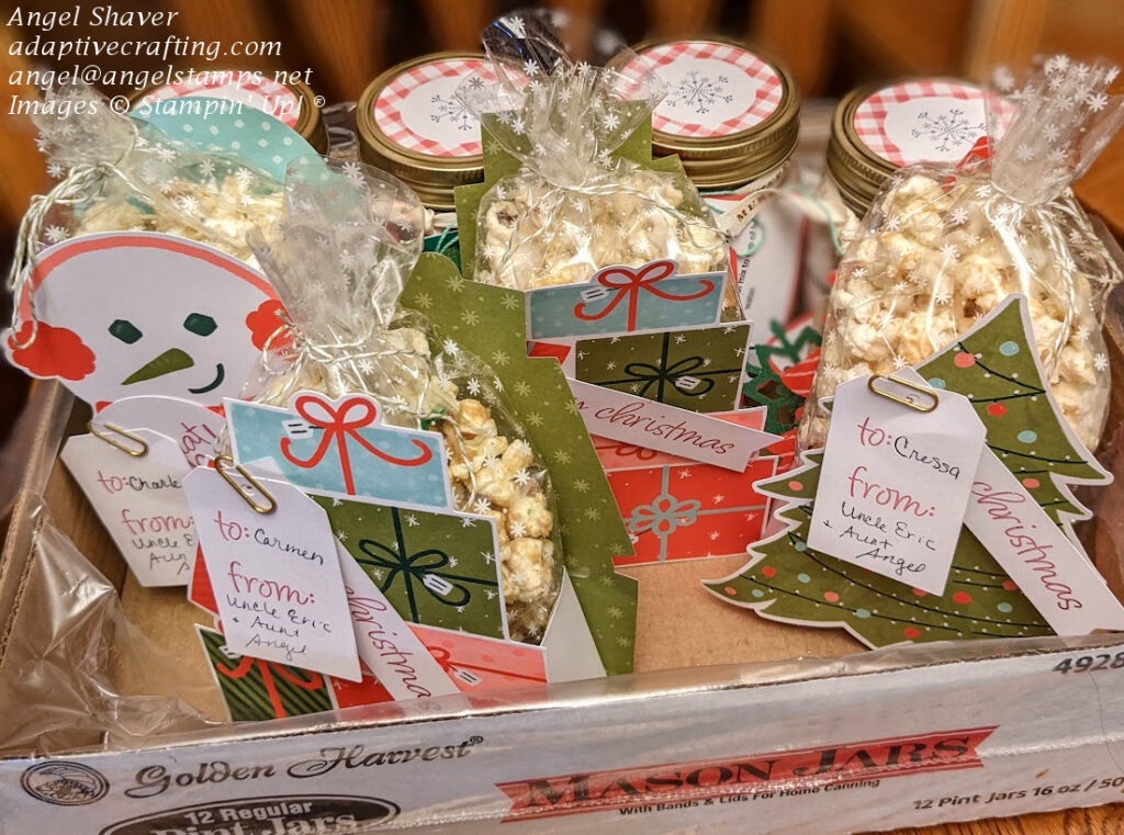 Jars of Hot Chocolate mix and packages of gingerbread popcorn in Paper Pumpkin November 2021 gift packages--a snowman, Christmas tree, and packages of presents.