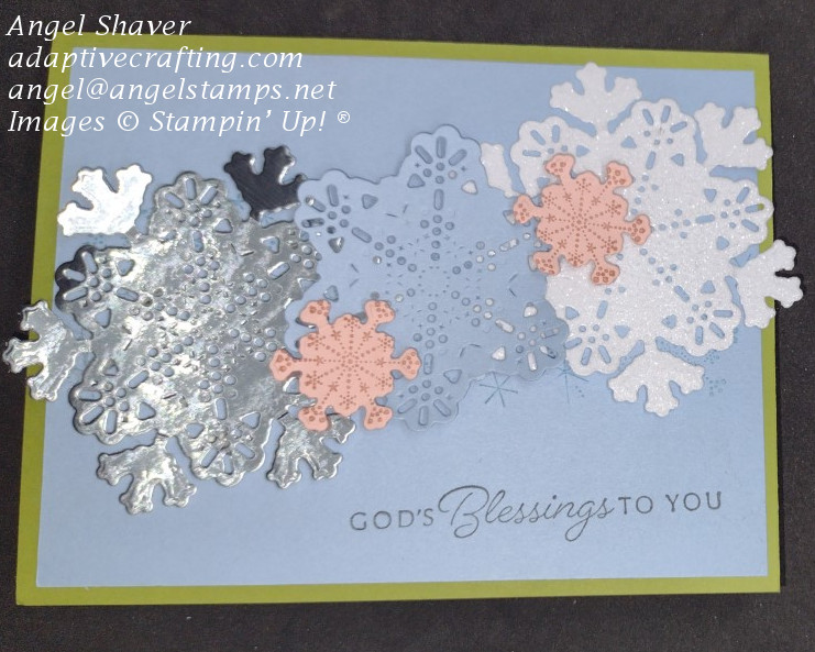 Green Christmas card with blue card front with stamped blue snowflakes and snowflake dies in pink and blue cardstock, silver foil, and white glimmer paper across front.  Sentiment says, "God's Blessings to you."