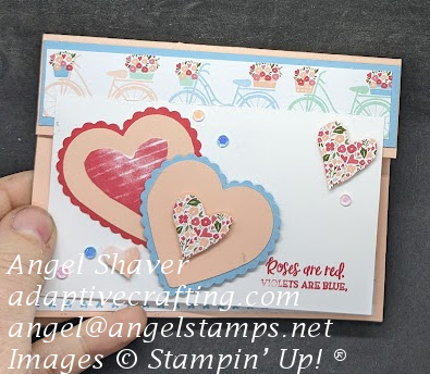 Pink card with a small fold down flap with patterned paper with bicycles.  White rectangle attached to front with layered hearts and sequins.  Sentiment says "Roses are red. Violets are blue."