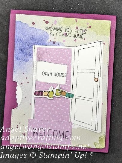 Purple card with background paper with blobs and splatters of color.  Diecut of open door with two arms with cups stretching across door.  Welcome mat in front of door.  Rotating wheel of sentiments says "Open house." Sentiment at top of card says, "Knowing you feels like coming home."