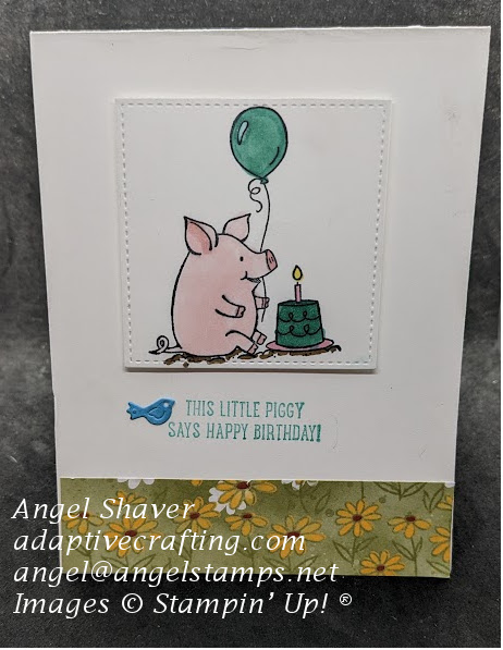 White birthday card with stitched square with stamped pig with birthday cake and balloon.  Strip of patterned paper with daisies on bottom of card front.  Sentiment says, "This little birthday says happy birthday," with blue bird die.