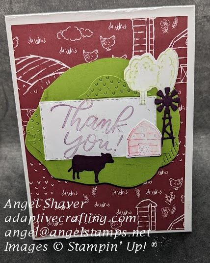 White card with farm scene patterned paper.  Sentiment rectangle with green hill dies creating a frame and dies of farm scene, trees, barn, windmill, and purple cow.