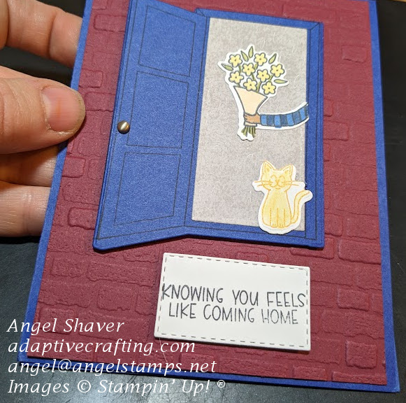 Blue card with red brick layer with blue door opening to welcoming party--orange cat and hand holding flower bouquet.  Door mat says, "Knowing you feels like coming home."