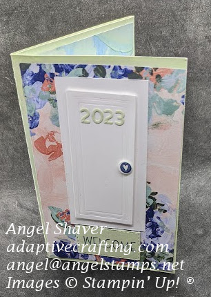 Green card with patterned paper with abstract splotches of color.  Closed white door die with 2023 in green and green welcome mat.