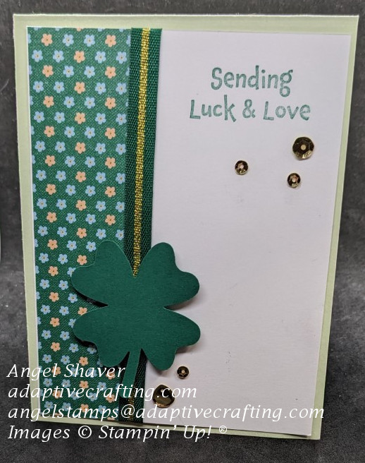 Green card with patterned paper with flowers, a green and gold ribbon, and a four-leaf clover punch  Sentiment says" Sending luck and love"  Gold sequins add bling.