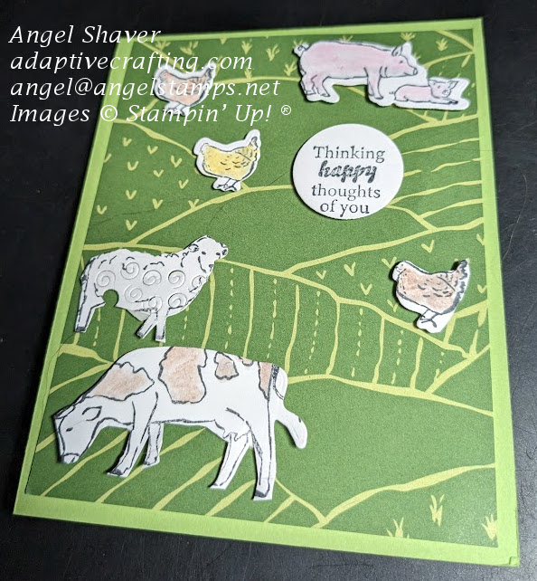 Green card with patterned paper of rolling green hills.  There are farm animals stamped and die cut and adhere to the card front.  Sentiment circle says, "Thinking happy thoughts of you."