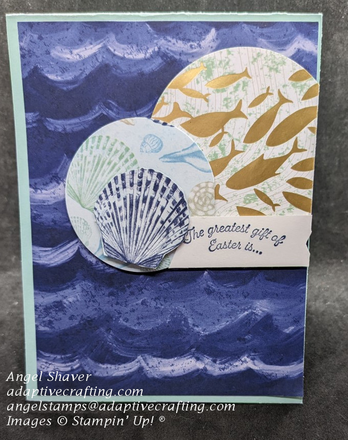 Blue card with wave patterned paper on front and two circles of patterned paper --one with a school of gold fish and one with various shells.  Sentiment label says, "The greatest gift of Easter is  . . ."