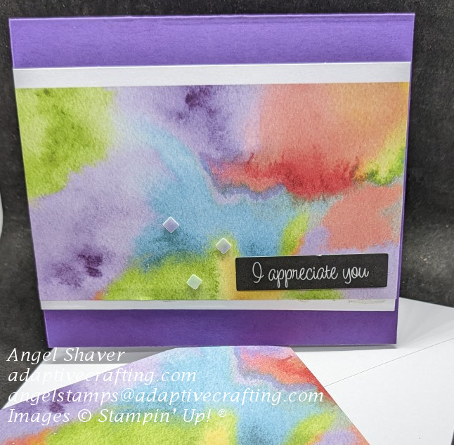 Purple card with layer of patterned paper with watercolor wash in rainbow colors.  Sentiment says, "I appreciate you." and has irridesent diamond sequins.