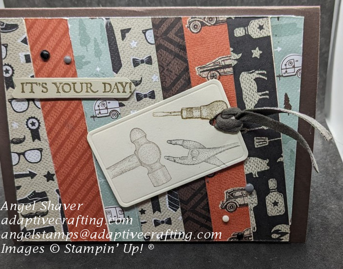 Brown card with background made of masculine printed pattern paper strips.  Tag with vintage tools on front.  Sentiment label says, "It's Your Day!"