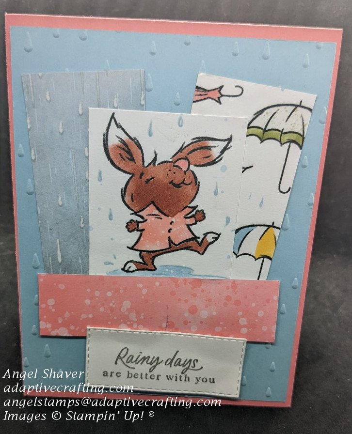 Pink card with blue card layer embossed with raindrops.  Panels of rain and umbrellas patterned paper.  Sentiment label says "Rainy days are  better with you."