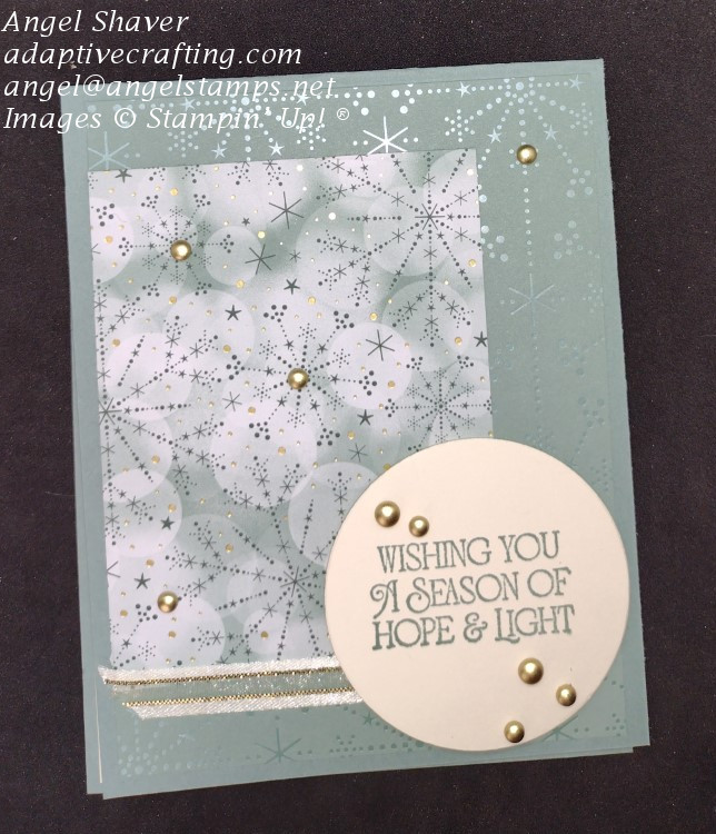 Soft green card with layers of glittering snowflake patterned paper with touches of gold.  Sentiment circle says, 'Wishing you a season of hope & light."