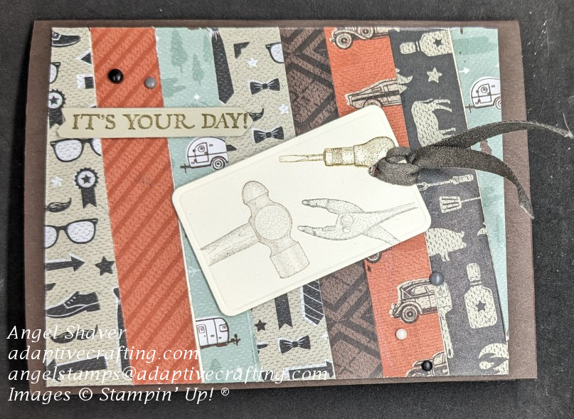 Brown card with background made of masculine printed pattern paper strips.  Tag with vintage tools on front.  Sentiment label says, "It's Your Day!"