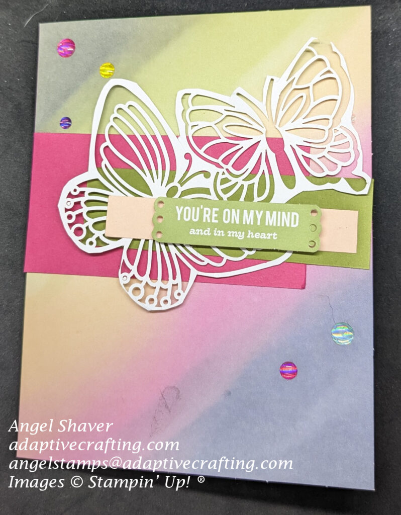 Card with rainbow wash background.  Strips of cardstock in bright pink, green, and lighter pink.  Cut out butterrflies are featured on the card front.  Sentiment says, "You're on my mind and in my heart."  