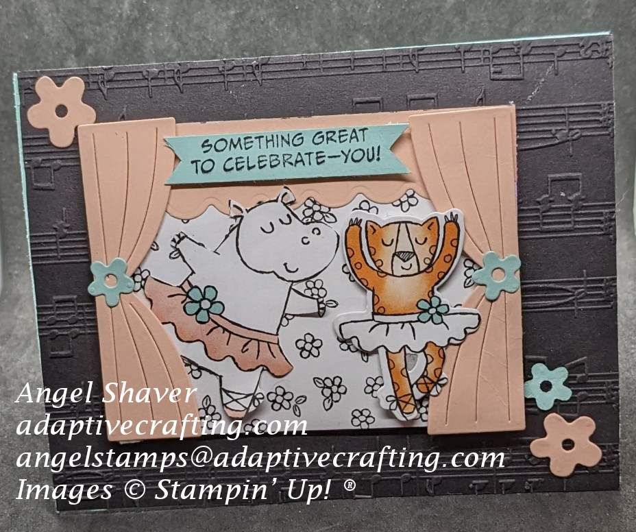 Card with black background embossed with music.  Featured layer at center of card is stage with pink curtains and floral backdrop.  Two animals wearing tutus and ballet slippers are dancing on the stage--a hippo and a leopard.  Card also features pink and blue flowers.  Sentiment label at top of stage says "Something Great to Celebrate--You!"