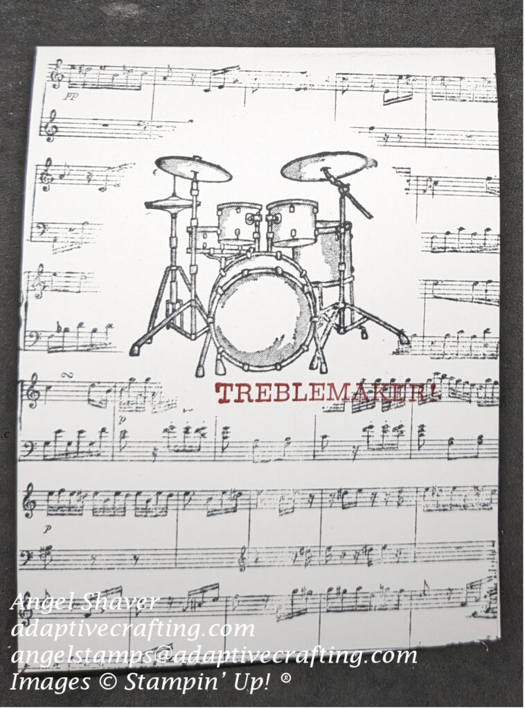 White card with music background stamp stamped over masking paper to create frame for stamped drum set.  Sentiment says "Treblemaker."