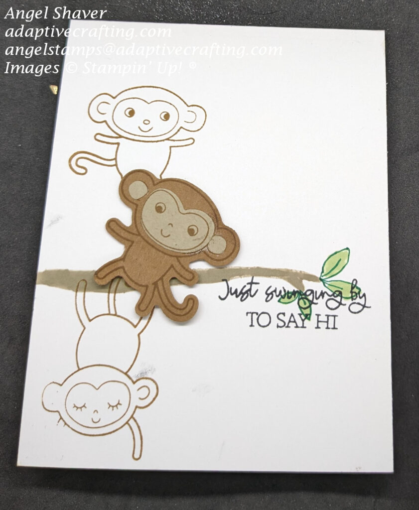 White card with branch with green leaves stamped across card front.  
There are two monkeys stamped on left side of card with one swinging from the branch.  Punch art brown monkey is positioned between two stamped monkeys.  Sentiment says, "Just swinging by to say Hi"