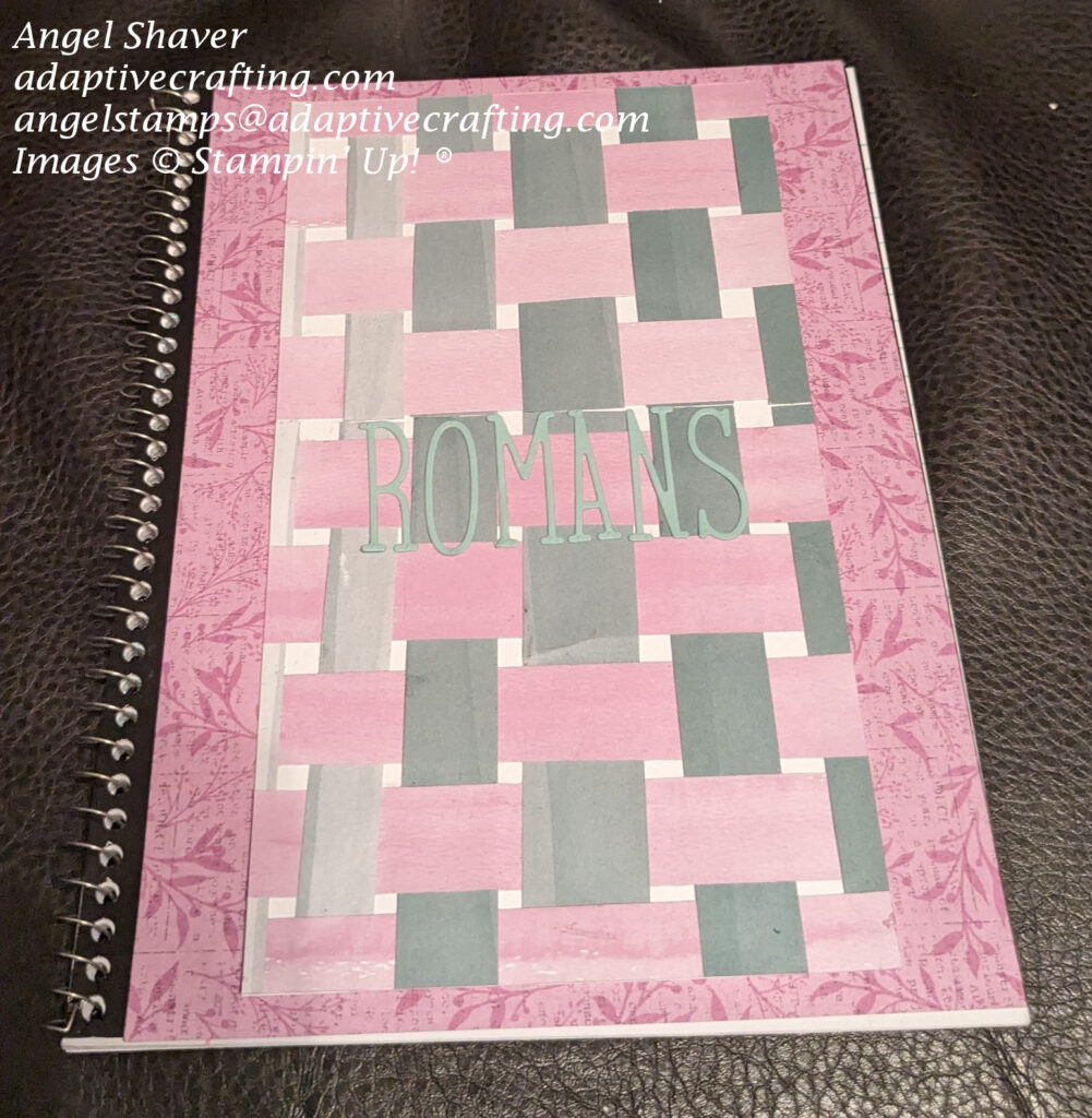 Spiral notebook covered with fresh freesia colored patterned paper with leaf pattern.  Then a piece of white cardstock with pink and green strips of paper woven together on top.  Finally, diecut letters spelling Romans is adhered to the center of the notebook front.