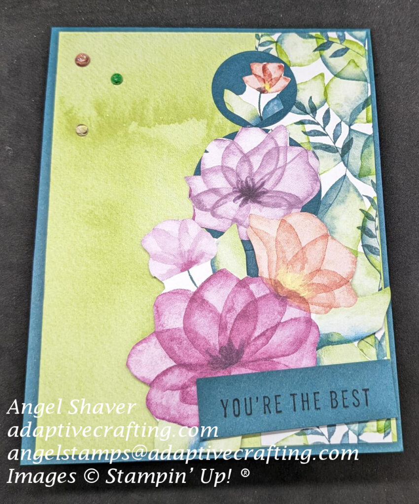 Dark teal card with green background paper on left 2/3 of card.  Right 1/3 has strip of patterned paper with lots of leaves.  Three circles run vertically up the card at the left edge of the leaf patterned paper.  All three circles have flowers cut from patterned paper The sentiment label at the bottom of the card says, "You're the Best."