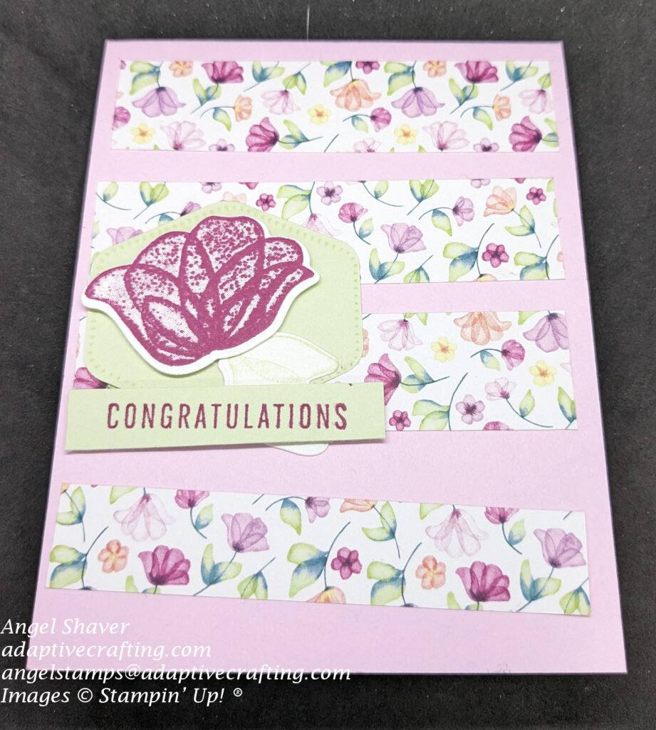 Pink card with four horizontal panels of  pattern paper with small flowers.  On top of that is light green hexicon punch with a pink diecut flower with light green leaves.  Sentiment label says, "Congratulations"