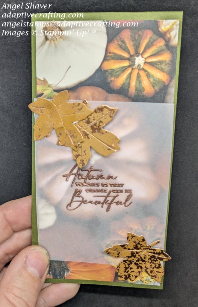 Green slimline card with photo realistic pumpkin patterned paper on card front.  Top layer is vellum with heat embossed sentiment that says, "Autumn teaches us that change can be beautiful."  Vellum layer has die cut maple leaves at two corners.