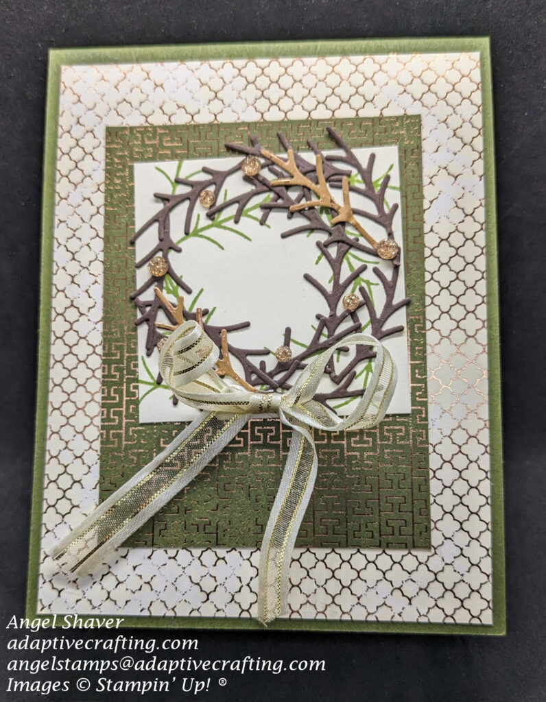 Green card with Very Vanilla and green paper layers accented with copper to create tile pattern.  Top layer shows wreath created with stamps and dies that look like branches.  Wreath is decorated with gold sparkle dots and a vanilla and gold ribbon.