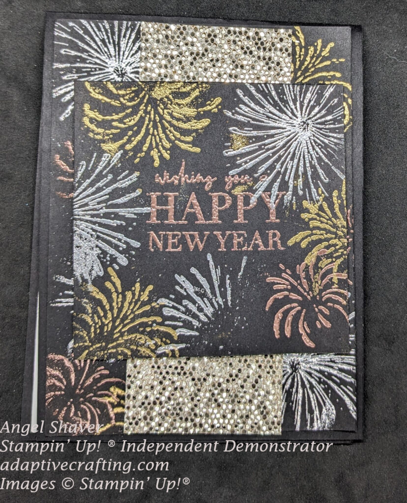 Black card with silver, gold,, and copper heat embossed fireworks on background layer and top focal square.  Includes strip of sequined glimmer paper.  Sentiment says, "Wishing you a Happy New Year."
