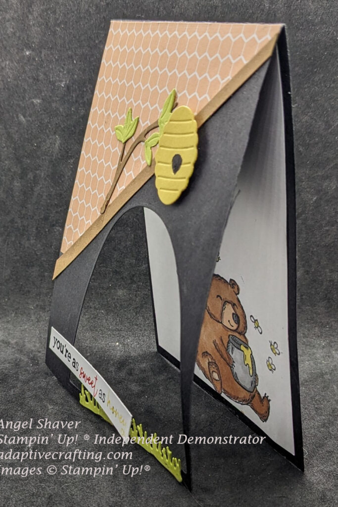 Angle view of black card that shows detail of cut out window in card front and stamped bear and bees on card interior.