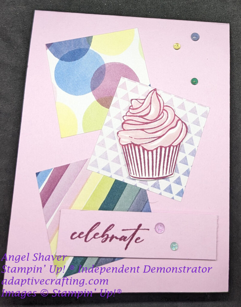 Pink card with three squares of different patterned paper.  1.  Different colored circles.  2.  pink and blue triangles  3.  brightly colored diagonal stripes..  There is a cupcake with pink frosting on the center square.  The sentiment says, "celebrate." The card has various colored tinsel dots.
