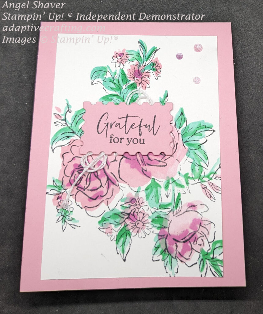 Pink card with large stamped image of bundle of roses and flowers which are colored with pink and purple flowers and leaves of green.  Sentiment label says, "Grateful for you." with white twine bow beneath label.  Finished with pink and purple sparkling gems.