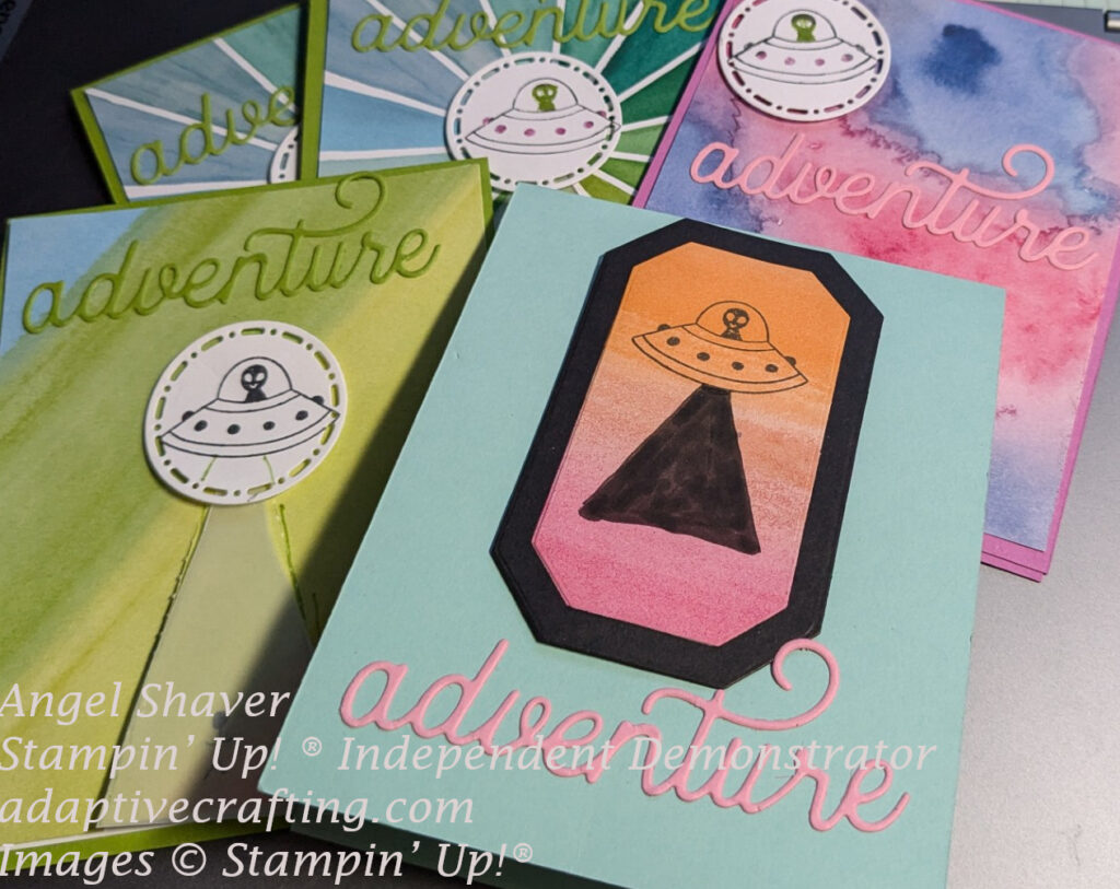 Picture of five similar yet slightly different cards using an alien in a spaceship stamp, Full of Life patterned paper in bright colors and an "adventure" word die.