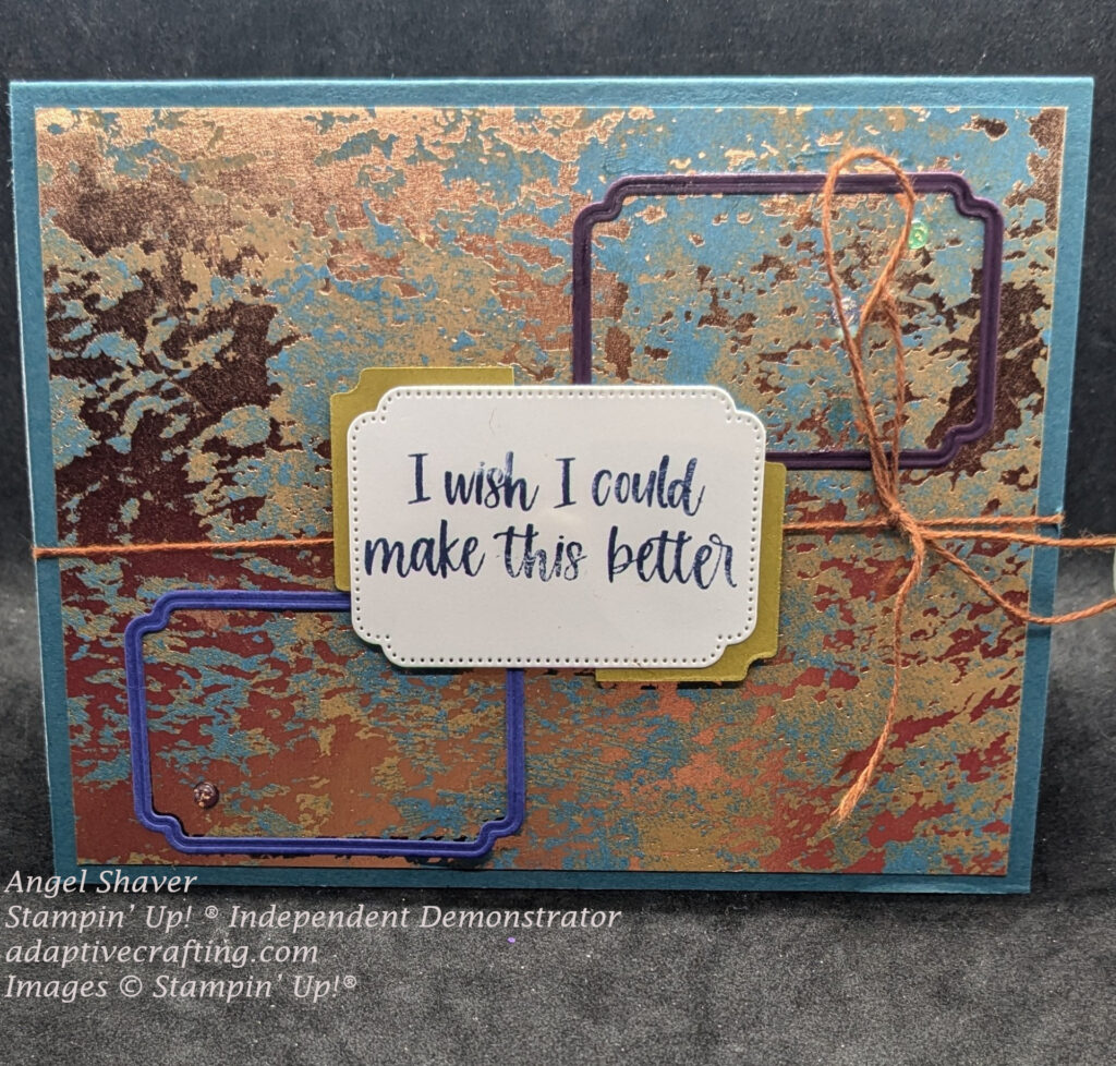 Teal card with teal and copper card splash patterned paper card layer.  A brownish thread is tied around card front.
Blue frame die is a bottom left corner, purple die frame at top right corner and sentiment label with yellow die behind it is in center of card.  Sentiment says, "I wish I could make this better."