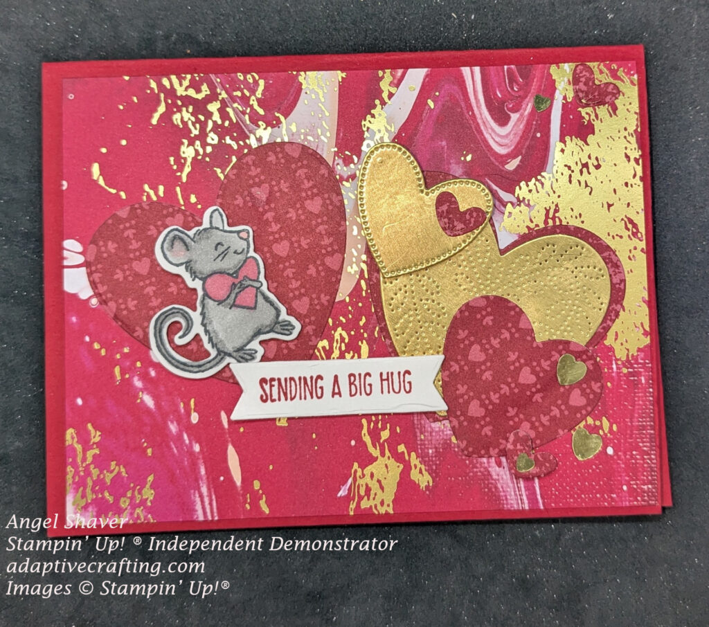 Red card with red, white, and gold swirled patterned paper.  Diecut hearts in borth a red wth pink hearts pattern and some gold hears.  Sentiment label says, "Sending a big hug."  Mouse hugging a pink hearrt is stamped, diecut, and colored gray.