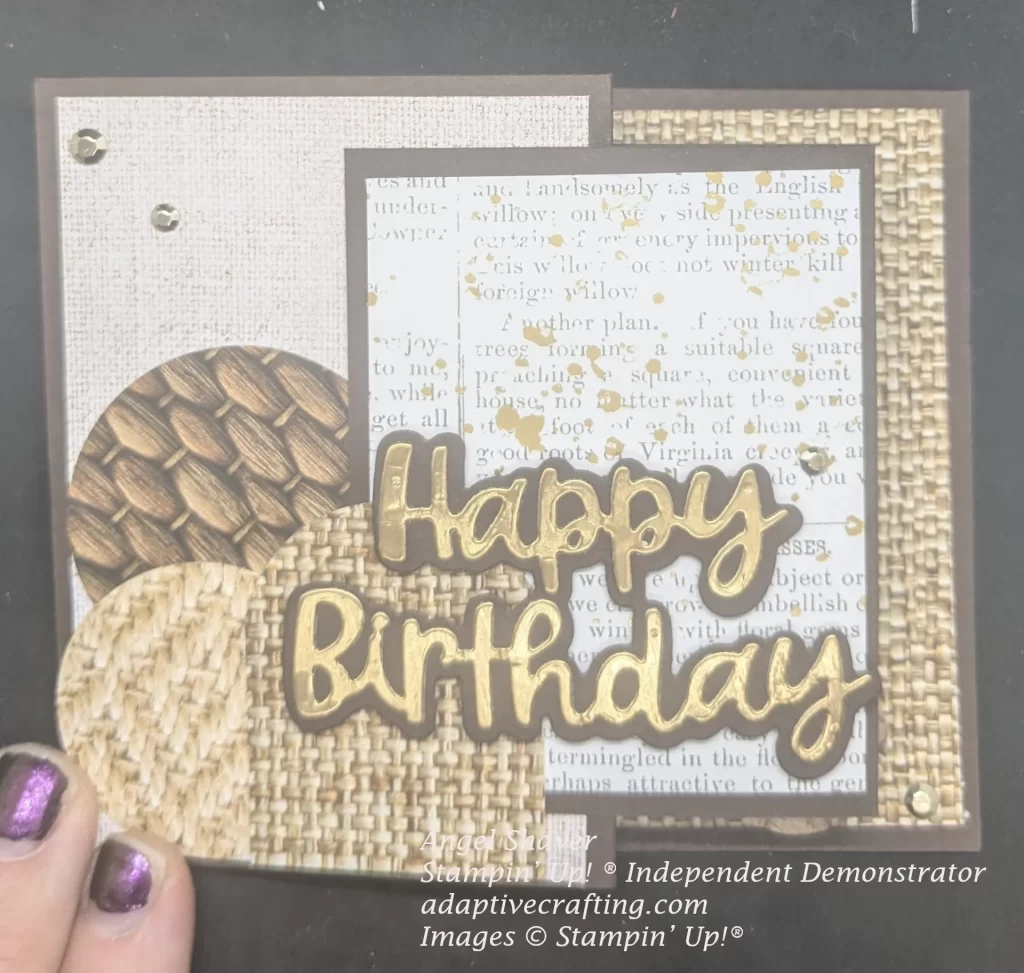 Brown card with different woven texture patterned papers on card and cut into circles and an arch. Center rectangle has patterned paper with type slattered with gold Die cut sentiment says "Happy Birthday" in gold foil with a brown background. Gold embellishments decorate the front.
