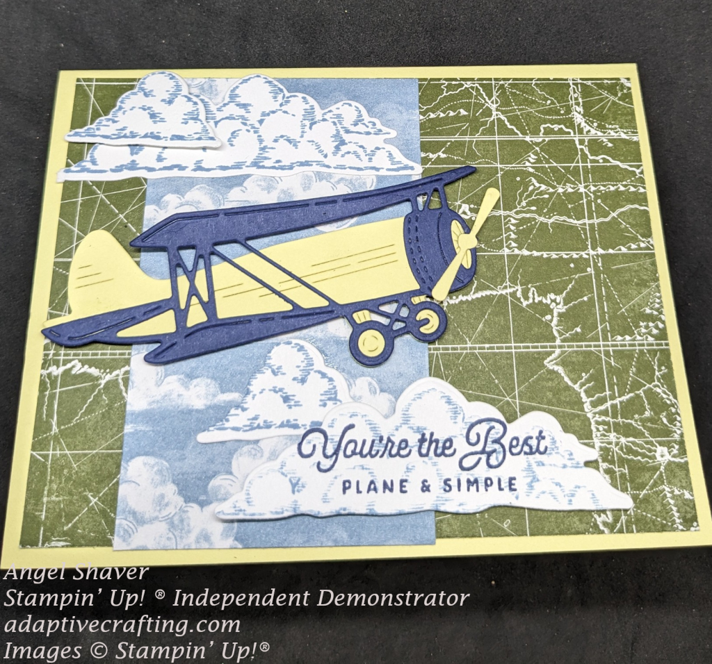 Yellow card with green topographical map patterned paper as background paper. Then strip of blue background paper with white clouds. The focal point image is a yellow and blue diect propeller plane and several stamped and diecut clouds. One cloud has the sentiment stamped in it, "You're the Best Plane and Simple."