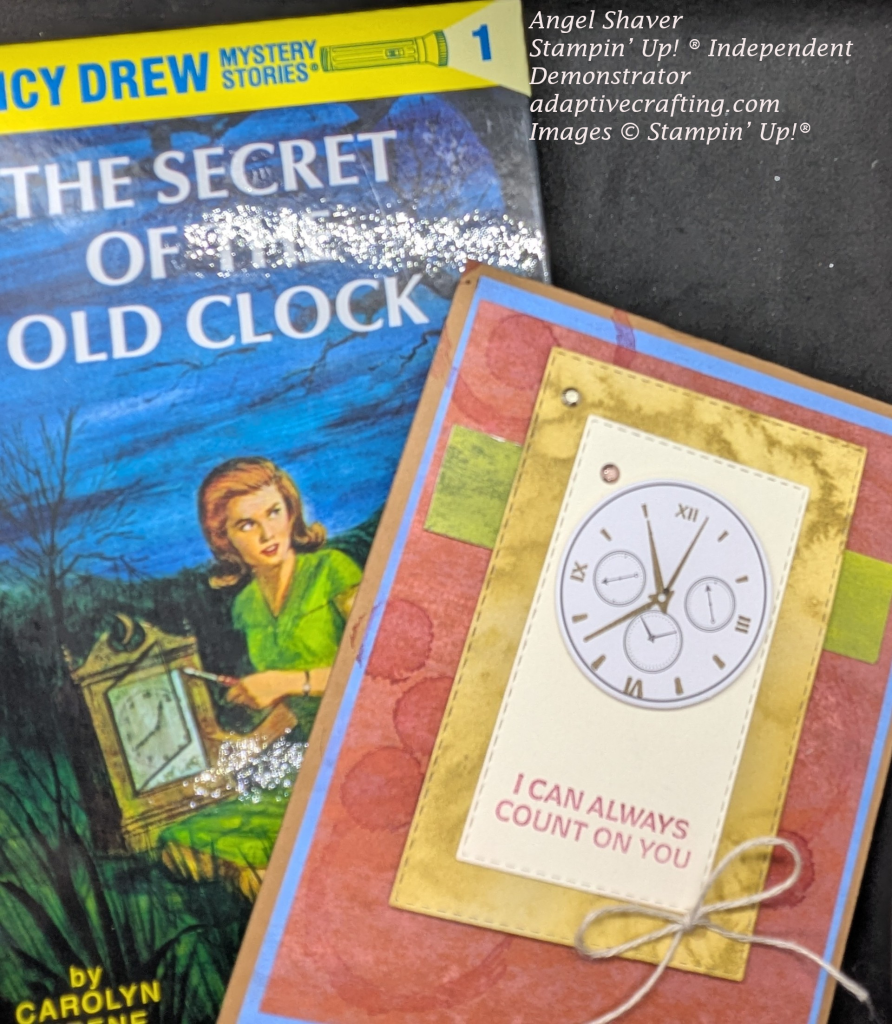 Picture of book Nancy Drew Mystery Stories1 The Secret of the Old Clock. Image of Nancy Dres holding a clock. Brown card with blue and red layers. Circles are stamped on red layer. Green strip of patterned paper runs horizontally across card. Stitched rectangle in gold with a cream colored rectangle with "I can always count on you." with clock at top of rectangle. Bow of linen thread is added to bottom of cream colored rectangle. Copper and gold embellishments are added to the front.