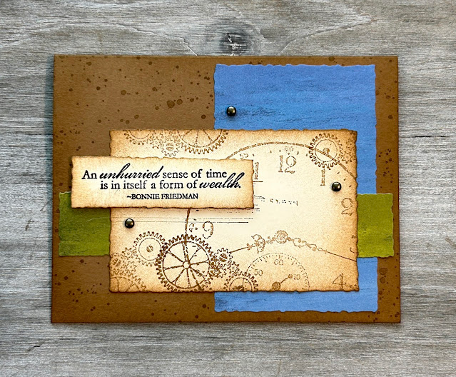 Brown card with blue rectangle on right side and green strip of patterned paper horizonal across center. Focal cream rectangle with gear and clocks stamped on it and edges darkened with brown ink. Sentiment rectangle says, "An unhurried sense of time is in itself a form of wealth. Bonnie Friedman"