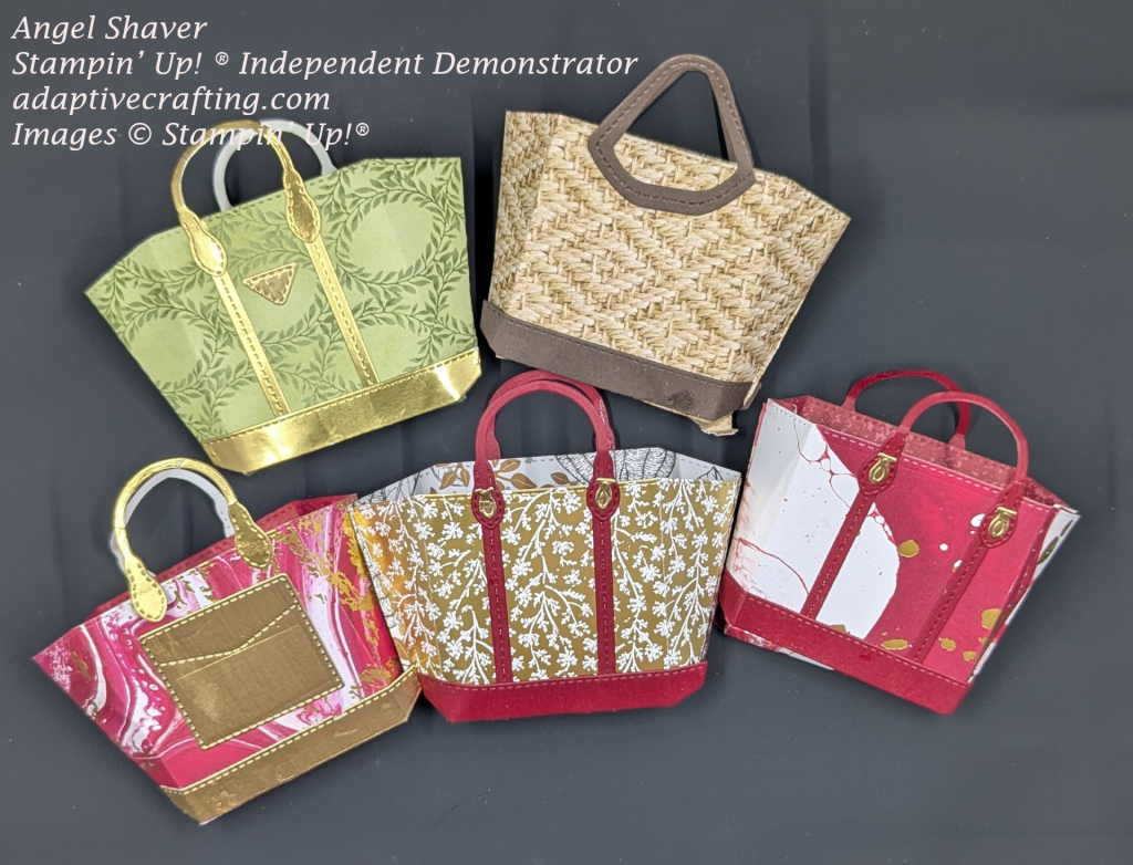 Five totes created with die cuts.  1.  Green with darker green leaves creating ovals.  Gold straps, handles, and triangle logo.  2. Crumbcake woven bag with dark brown bottom and handles.  3.. Red and white marble bag with gold bottom, handles, and pocket.   4. Gold bag with white flowers.  Red straps, bottom, and handles with gold fasteners.  5. Red and white marble tote with red bottom, straps, and handles with gold fasteners.
