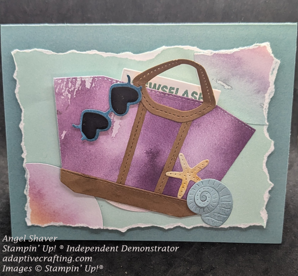 Teal card with lighter blue green paper on front with torn edges.  Blue, purple, and orange patterned paper semi-circles at top right and bottom left corners of torn paper layer.  Circle in center is covered by tote die in purple patterned paper with brown handle and straps.  There is a starfish and seashell at the bottom front of the tote bag.  Blue heart shaped sunglasses are hanging from the handle and there is a paper inside that says, "Newsflash"